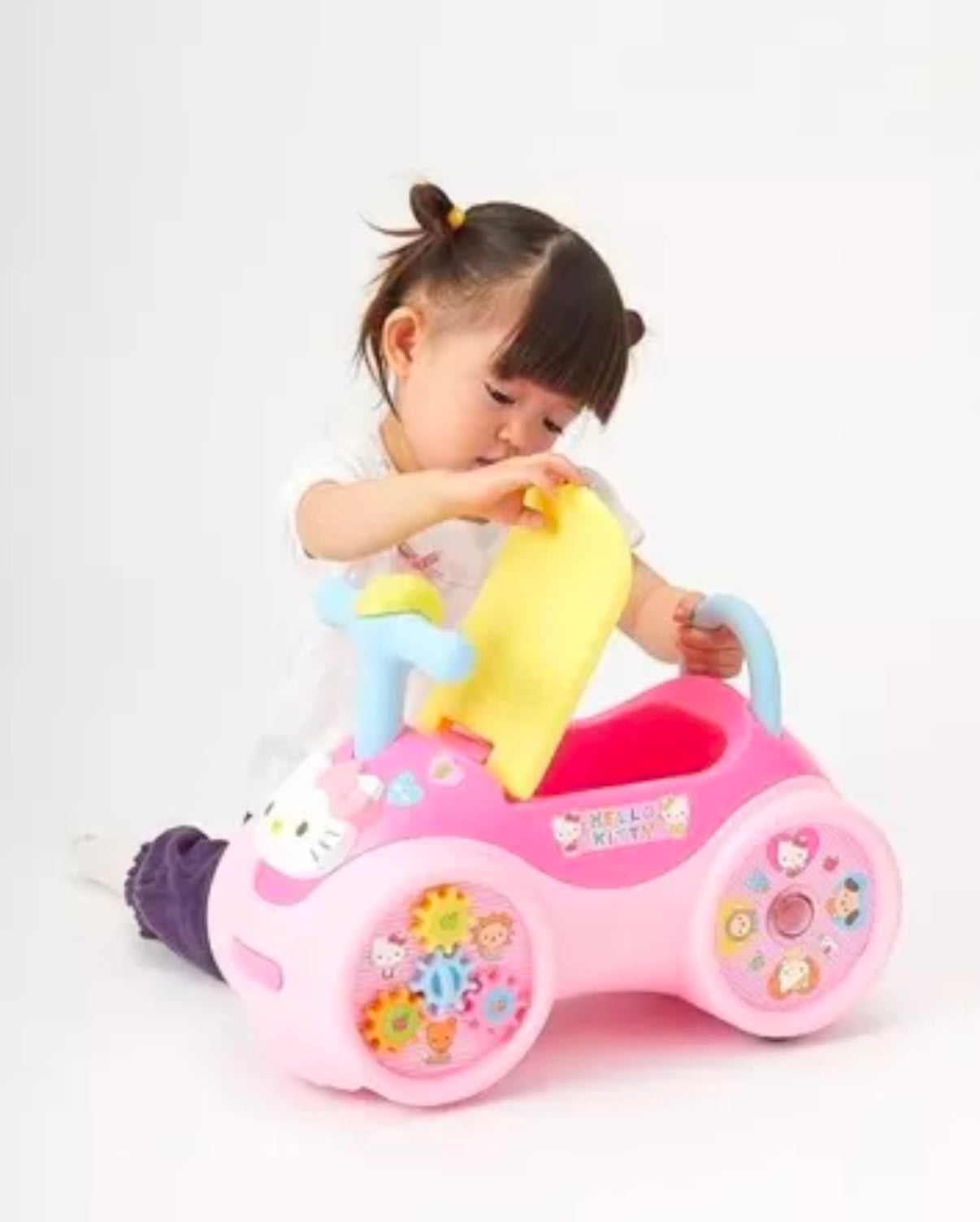 a child playing with pink foot-powered car toy